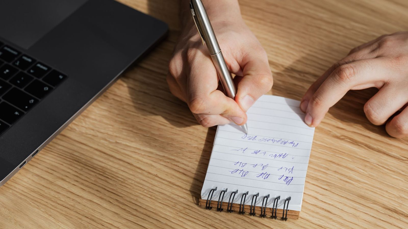 Un carnet de notes manuscrites a cote d'un ordinateur portable